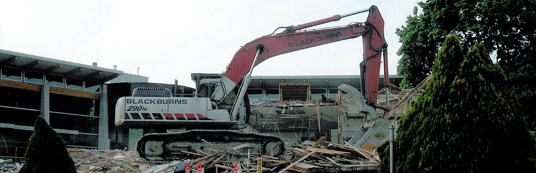 Excavator performing building demolition